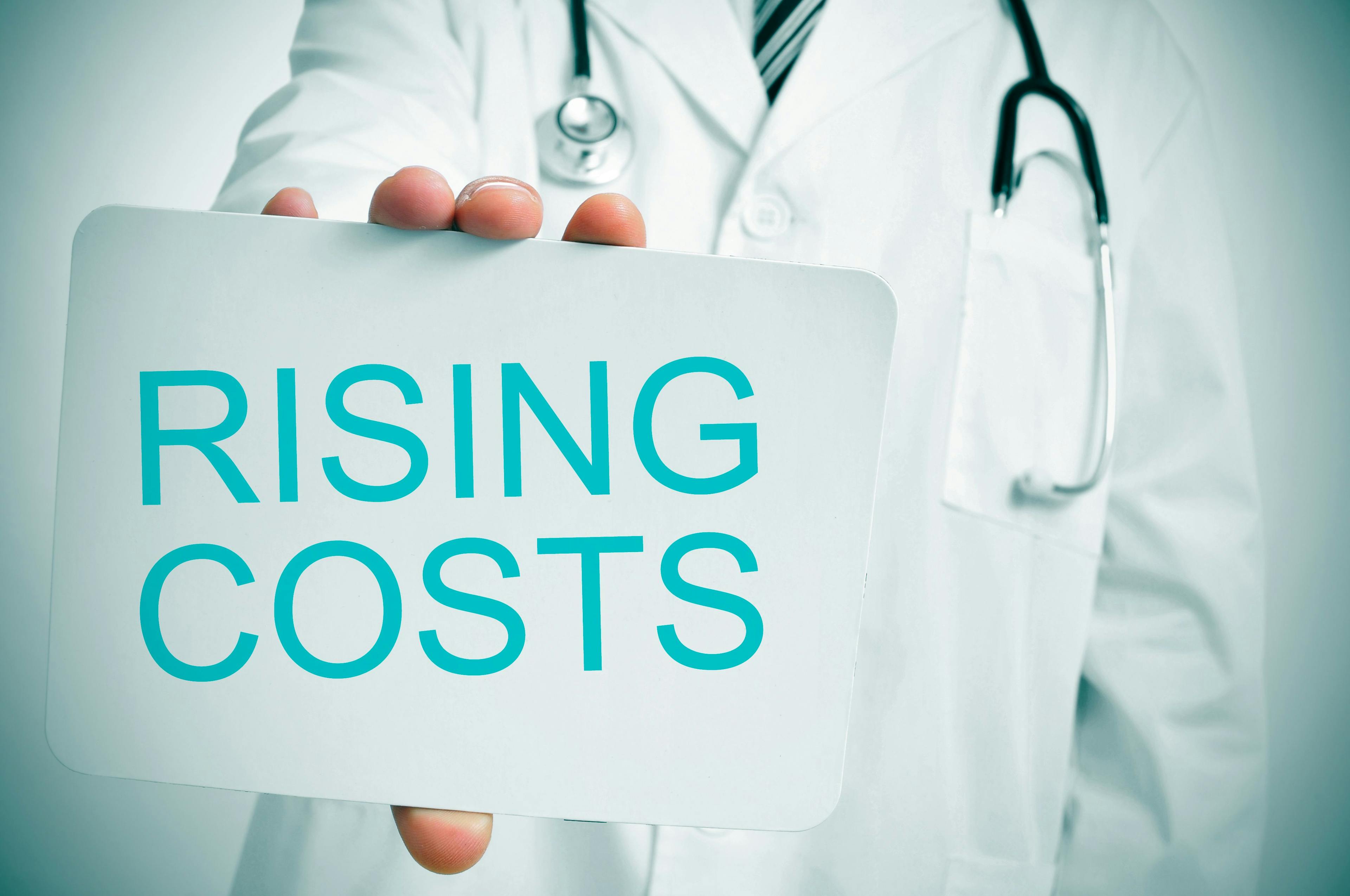 doctor holding "rising costs" sign ©nito-stock.adobe.com