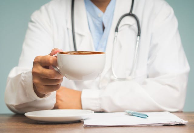 physician in uniform holding morning coffee: © meeboonstudio - stock.adobe.com