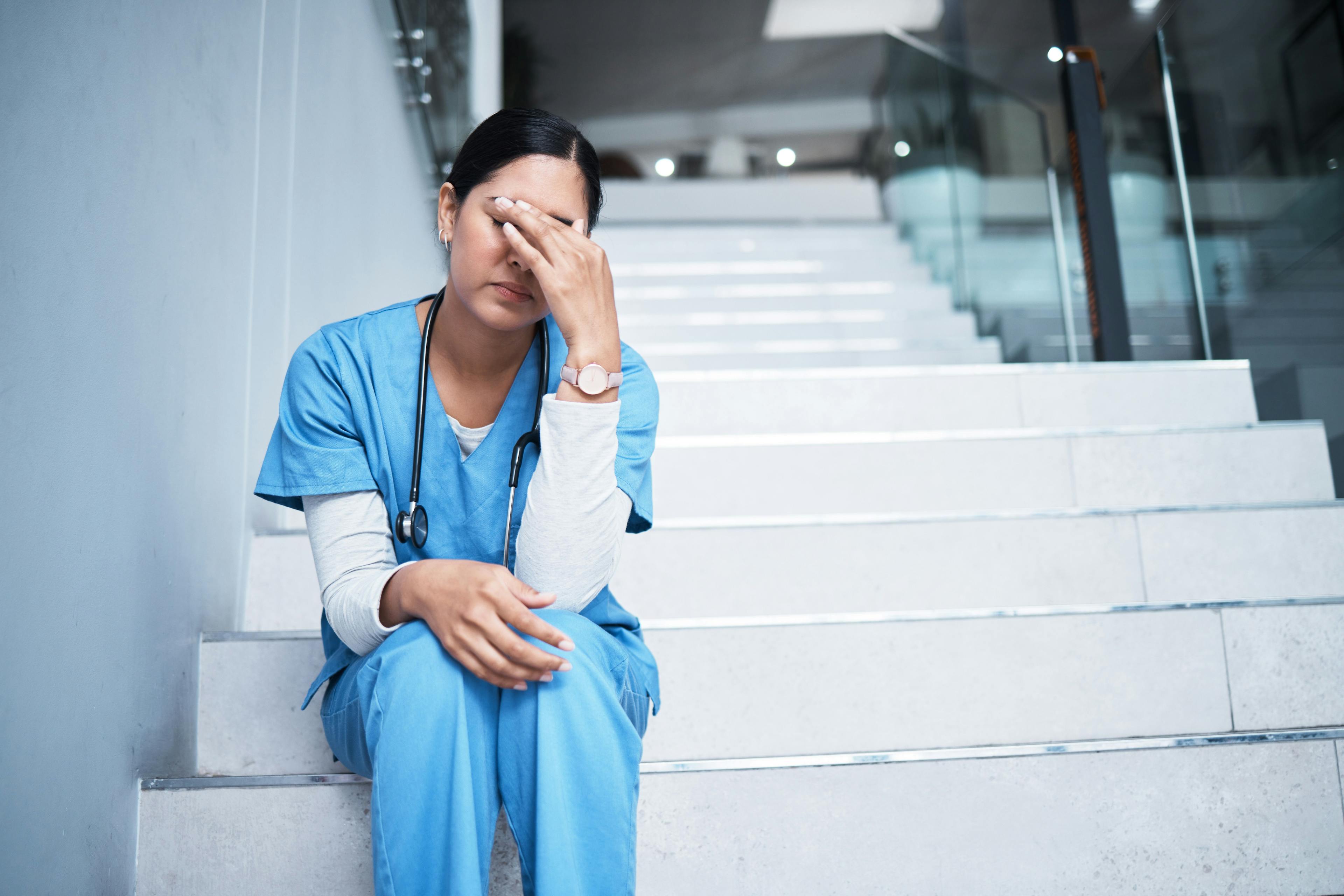Tired doctor in scrubs sitting on stairs ©Courtney Haas/peopleimages.com-stock.adobe.com