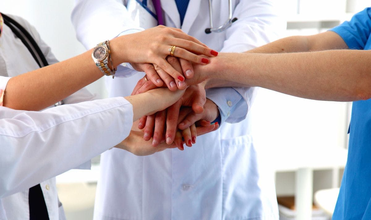 medical team stacking hands: © lenetsnikolai - stock.adobe.com