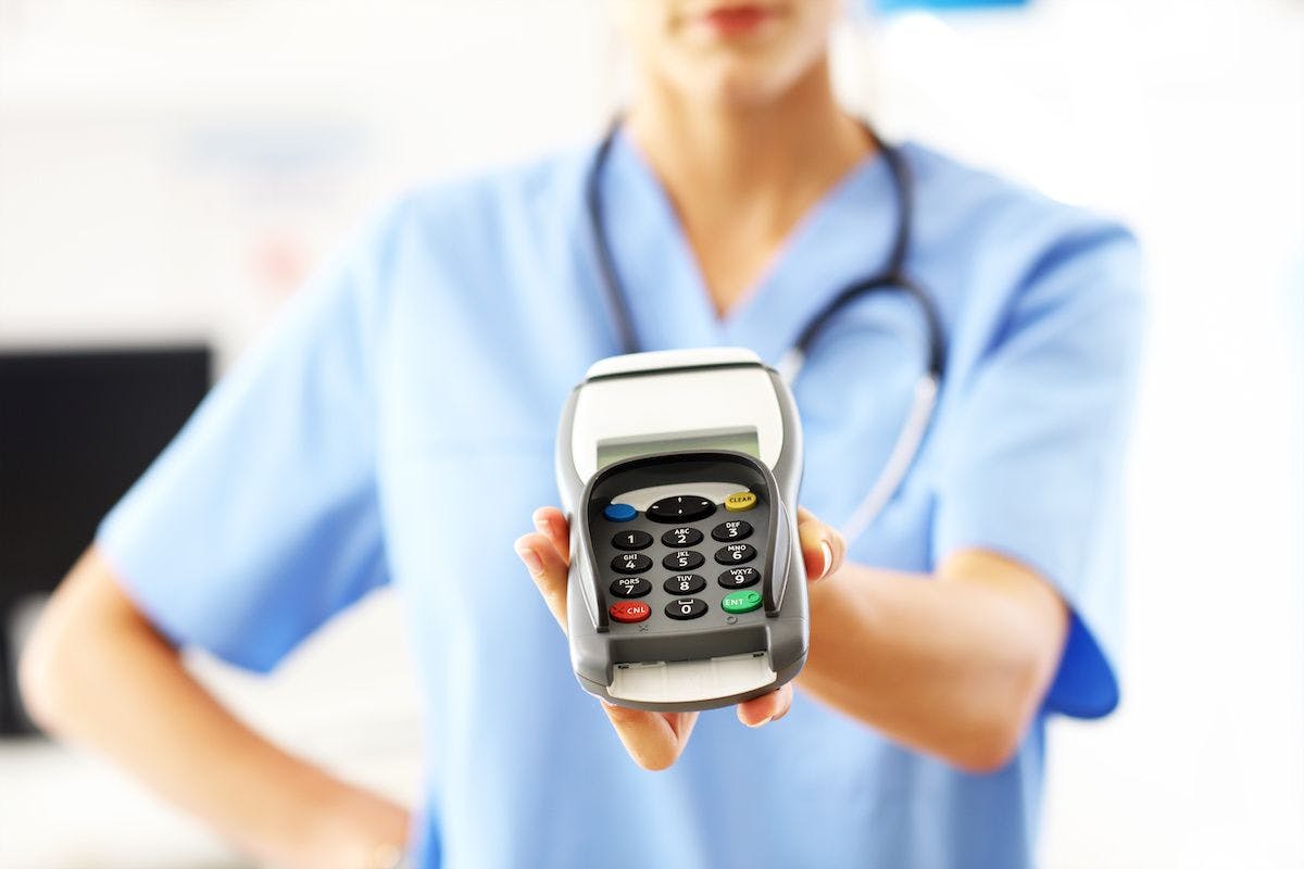 female doctor with payment terminal: © Kalim - stock.adobe.com