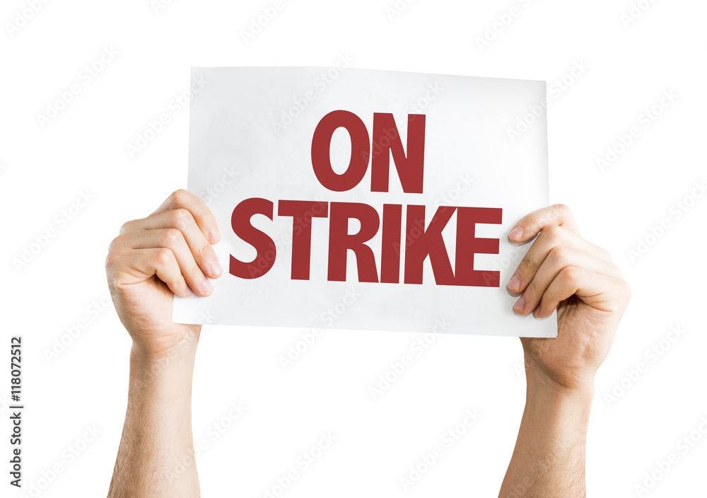 Person holding On Strike sign ©gustavofrazao-stock.adobe.com